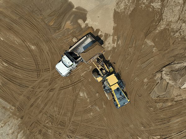 construction progress aerial drone photo of two trucks dumping and hauling sand