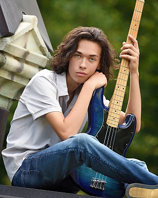 senior picture of louisville kentucky graduate. boy with long brown hair holding blue guitar