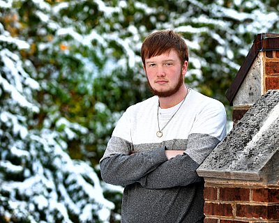 senior photography of louisville kentucky graduate. boy with red hair standing in front of frosted evergreen trees