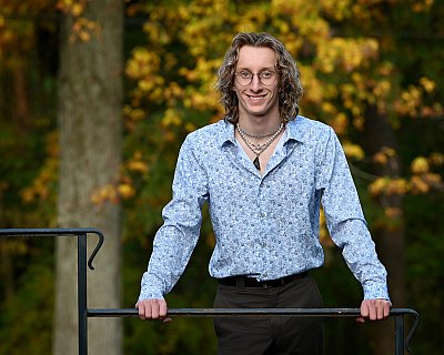 senior photography of louisville kentucky graduate. teenage boy with long curly hair posing in blue shirt