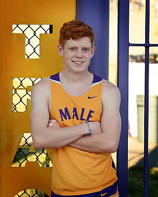 senior photography of louisville kentucky graduate. teenage boy with red hair posing in yellow and purple track athletic uniform