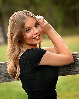 senior photography of louisville kentucky graduate. close up of teenage girl posing in black shirt with blonde hair. pasture in background