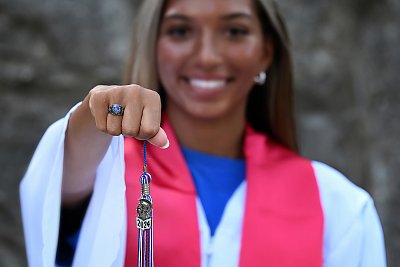 senior photography of louisville kentucky graduate. teenage girl in white and red graduation robe holding out graduation tassle year 2024