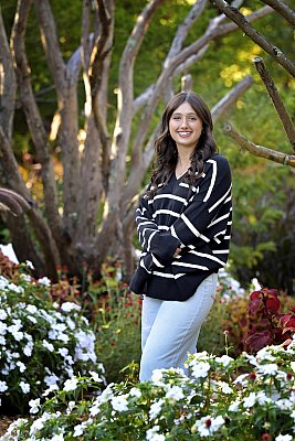 senior photography of louisville kentucky graduate. teenage girl in black-and-white striped shirt standing in front of white flowers