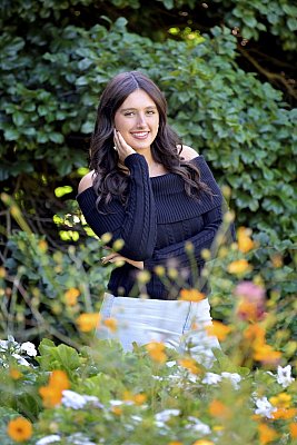 senior photography of louisville kentucky graduate. teenage girl with black hair and black shirt standing in front of yellow flowers