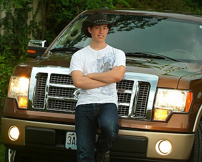 senior photography of louisville kentucky graduate. teenage boy wearing white shirt and cowboy hat, leaning on his brown truck