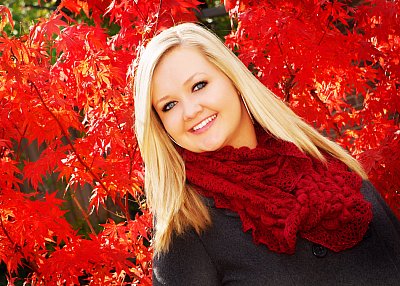 senior photography of louisville kentucky graduate. blonde teenage girl in black shirt and red scarf, posing in front of red fall leaves