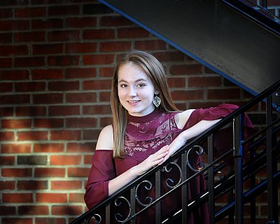 senior photography of louisville kentucky graduate. teenage girl in purple shirt leaning on black staircase